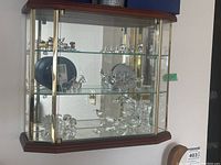 Front view of the wood and glass display cabinet with miniatures inside (not included in sale) showing glass shelves and wooden top and bottom framing.