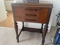 Full front view of chest showing three drawers, wooden pulls, baluster legs and stretcher