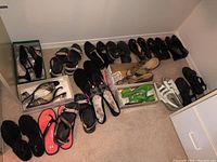 View of all 17 pairs of ladies shoes and sandals arranged on carpet floor including styles such as heels, flats, and casual sandals in black, coral pink, white-gray, green.