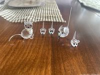 Cat and four mouse figurines on a wooden surface, showing relative size and grouping.