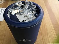 Three Swarovski crystal frog figurines with one partially inside a blue Swarovski box with white interior.