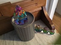 Multicolored Swarovski pyramid-shaped paperweight on original branded cylindrical box with three spherical paperweights aligned by size on marble surface.