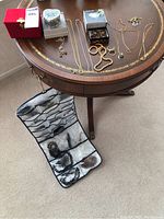Overview of table displaying vintage custom jewelry and multiple jewelry boxes, including a small portable jewelry roll-up organizer on the floor containing bracelets and necklaces.