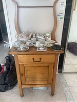 Antique pine washstand with lyre form towel rack, top showing tea set pieces (contents not included).