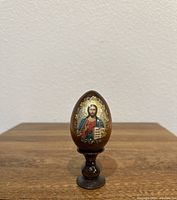 Front view of the wooden Easter egg showing Jesus Christ icon with gold leaf halo and decorative elements.