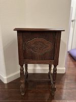 Front view of the vintage wooden smoking stand showing copper inlay on door and turned legs.