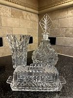 Front view of crystal butter dish, decanter, and vase on countertop
