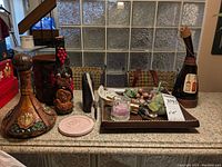 Full view of artisan style decorative bottles on countertop with ceramic tray containing decorative fruit and wine accessories