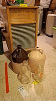 Photo showing two stoneware jugs, two clear glass milk bottles, and a Carolina washboard in the background.