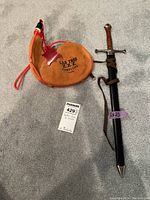 Photo of leather flask marked Las Tres Z.Z.Z. Pamplona alongside dagger in sheath on carpet.