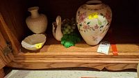 The four-piece set of ceramic decorative items displayed on a wooden shelf including the large Lenox vase, small beige vase, cream bowl, and swan figurine with grapes.