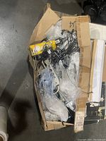 Box filled with assorted display lights, halogen lamps, and power strips seen from above in a cardboard box.