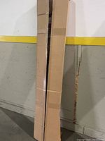 Two long cardboard shipping boxes containing wire shelving units standing vertically.
