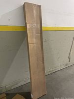 Tall rectangular shipping box standing upright, sealed and unopened containing the wire shelf.