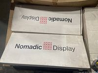 Two cardboard boxes labeled 'Nomadic Display' showing product branding and packaging