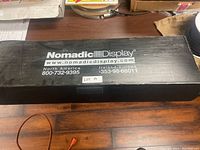 Black box with Nomadic Display branding and contact information on lid.