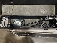 Pair of Nomadic halogen floodlights housed in metal case with cords and mounting hardware coiled inside.