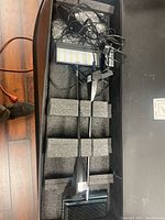 Two Nomadic LED flood lights set in foam compartments inside a black carrying case, wires coiled above.