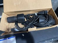 Box containing the pair of black Skandalight spotlights with cords coiled inside and included bulbs.