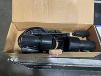 Top-down view of both black Skandalight spotlights with cords inside an open cardboard box.