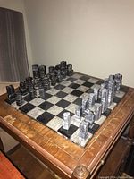 Image showing the full chessboard with black and light stone squares and all 32 chess pieces arranged at starting positions.