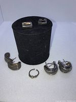 All 4 items displayed together on black cylindrical stand showing variety of earrings and nose ring.