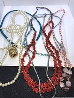 Top view of all 6 necklaces arranged inside a white box, showing diverse styles and colors including pearl, coral, turquoise, and pink beads