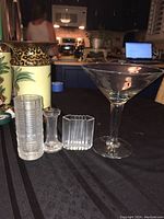 Overview of all four glass decor items on table, including martini glass, candlestick, and both vases.