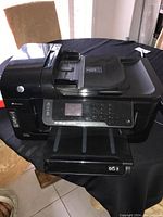 Full view of HP Officejet 6500A Plus printer showing paper input and output trays, control panel and scanner lid.