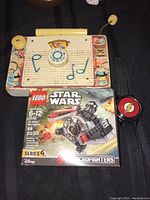 Photo showing vintage Fisher Price TV Radio toy, Lego Star Wars Tie Striker Microfighters box, and Flash DC Comics watch.