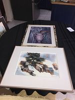 Two framed prints lying flat on a table, showing the overall view of the artworks and their frames.