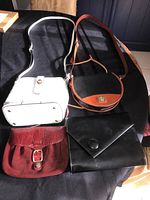 All four purses shown together on a black surface, with two standing and two lying flat, displaying front and body of each purse.