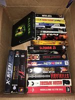 Stack of VHS movies including Aliens DVD on top, Top Gun, X-Men, and more identified by spine.