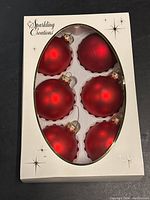Six matte red Christmas ball ornaments with gold caps in original box