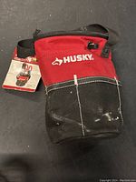Front view of red and black Husky small utility tool sack with strap and Husky logo.