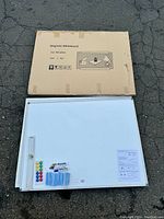 Magnetic dry-erase board laid flat beside its original cardboard packaging labeled 36x48 inches.