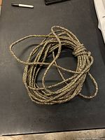 Full coil of braided camouflage rope on a dark surface.