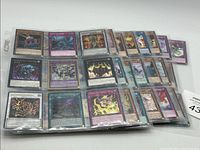 Several 1st Edition Yu-Gi-Oh! cards in protective sleeves arranged in groups, showing varied card types including monster, spell, and trap cards with colorful artwork.