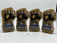 Four Marvel Avengers Infinity Gauntlet-shaped puzzle tins, all identical and unopened, shown from the front with clear view of shape and packaging.