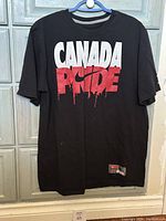Front of black Nike t-shirt with large front print 'CANADA PRIDE' with red Nike swoosh.