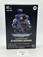 Front and side views of the boxed JOYTOY Warhammer 40k Ultramarines Incursors Vanguard Space Marines figure. Box shows figure image, 1/18 scale, and branding.