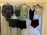 Full view of all 7 bohemian clothing items hanging against white curtain background, showing styles and colors.