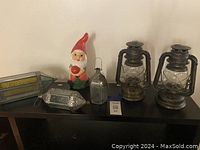 Overview photo showing all six items on shelf against wall: two battery lanterns, three Moroccan lanterns, and garden gnome
