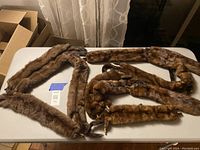 Photo showing all three vintage mink fur stoles laid out on a table, visible color and texture differences among the stoles.