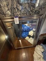 Photo of large rectangular mirror with wide metallic silver frame showing reflective glass and frame detail.