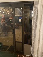 Photo showing bronze sliding glass door panel installed, with view of patio area through glass, highlighting integrated pet door at bottom.