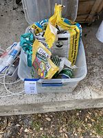 Clear plastic bin holding three bags of gardening products: Premium Outdoor Potting Mix, Dr. Earth organic potting soil, and a bag of Horticultural Perlite