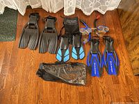 Photo of assorted snorkeling fins and two snorkeling masks with snorkels on wooden floor