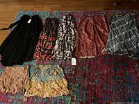 Seven women's skirts and shorts laid out on carpet, showing front and patterns.