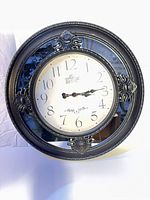 Front view showing ornate black resin frame and clock face